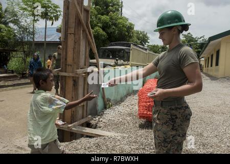 La Marine américaine lance le Cpl. Brook Klahn, droite, donne une Balikatan autocollant pour un garçon à un projet d'assistance civique d'ingénierie à l'appui de site Balikatan 2017 à Ormoc City, Leyte, le 14 mai 2017. Service des États-Unis et des Philippines ont travaillé ensemble pour construire de nouvelles salles de classe pour les élèves de l'école élémentaire de Don Carlos. Balikatan est un américain annuel-exercice militaire bilatérale des Philippines a porté sur une grande variété de missions, y compris l'assistance humanitaire et les secours en cas de catastrophe, la lutte contre le terrorisme, et d'autres opérations militaires conjointes. Banque D'Images