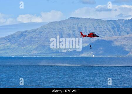 L'équipage d'une station d'Air Point MH-65 barbiers hélicoptère Dauphin soulève leur sauvetage nageur pendant un exercice de recherche et sauvetage en mer dans les environs de Ko'olina à Kahe Point, Oahu, le 29 novembre 2018. L'effort a abouti à la découverte d'Oscar, la personne simulée en détresse, environ deux heures après l'appel initial. Banque D'Images