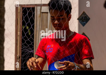 Don Daeng, Laos - 27 Avril 2018 : les pêcheurs de la réparation d'un filet de pêche dans la cour de sa maison dans une région rurale isolée du Laos Banque D'Images