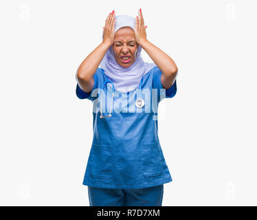 L'âge moyen des infirmières arabes senior woman wearing hijab sur fond isolés souffrant de maux désespérés et souligné parce que la douleur et la migraine. Ha Banque D'Images