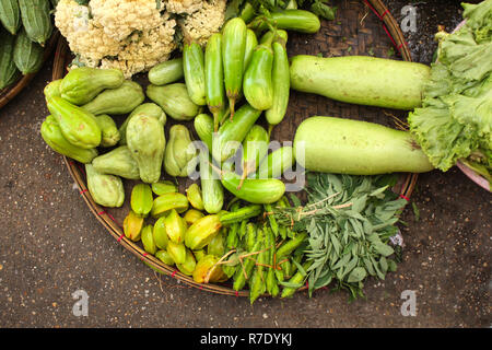 Légumes frais au panier en osier - le concombre, l'oignon, courge amère, les haricots verts, les courges, la salade, la carambole, le matin au marché chinois, Yangon, Myanmar Banque D'Images