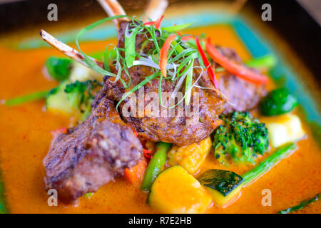 Jarret d'agneau grillé avec légumes grillés sur un lit de curry doux Banque D'Images