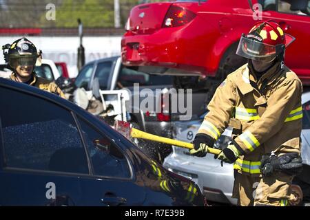 Gary Purcell et Robert Jacobs, Grissom pompiers, briser les vitres d'une voiture pendant la formation de désincarcération au Pérou, de l'Indiana, le 12 avril 2017. Grissom le service des incendies a une réponse immédiate la zone autour de la base qui peut être prolongée si l'urgence le justifie. Banque D'Images