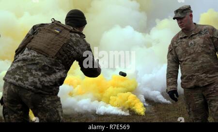 Le Sgt. 1re classe Conrad Martin [droit], un observateur/Coach Trainer avec le Centre de préparation interarmées multinationale observe un soldat ukrainien qu'il lance une grenade fumigène au cours de la préparation de l'exercice Combined Résoudre XI le 1 décembre à Hohenfels Secteur d'entraînement, de l'Allemagne. CBRXI exercice permet l'Armée américaine à l'échelle régionale alloués forces de combat pour l'Europe la possibilité d'exécuter un centre d'instruction au combat de la rotation avec un environnement multinational, la preuve de leur intégration dans les opérations de l'Europe de l'armée américaine. Banque D'Images