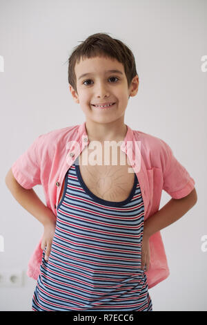 Happy little boy looking at heart love symbole dessiné sur sa poitrine isolé sur fond blanc Banque D'Images