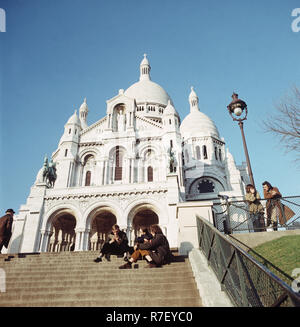 Les jeunes gens s'asseoir sur l'escalier en face de la basilique du Sacré-Cœur de Montmartre à Paris, France, en novembre 1970. La basilique est située sur la colline de Montmartre. Photo : Wilfried Glienke | conditions dans le monde entier Banque D'Images