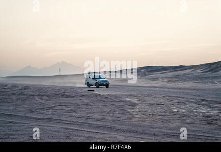 Hurghada, Egypte - Février 26, 2017 : voiture ou jeep, véhicule tout terrain, la conduite dans les dunes de sable du désert, sur fond de ciel blanc en surface. Safari et l'aventure. Voyage, voyage. Paysage aride Wanderlust Banque D'Images