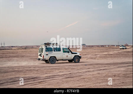 Hurghada, Egypte - 26 Février 2017 : safari dans le désert. Véhicule hors route, voiture blanche ou jeep la conduite dans les dunes de sable sur fond de ciel gris. L'activité extrême. La découverte et l'aventure. Locations et wanderlust Banque D'Images