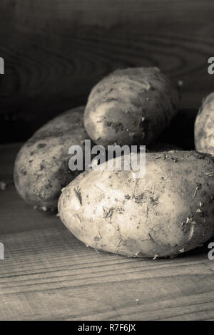 Des pommes de terre biologiques sale fraîchement cueillies sur un fond de bois avec la tonalité Banque D'Images