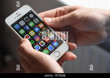 Teenage boy holding a mobile phone Apple iPhone SE afficher divers liste Rendez-vous. Banque D'Images