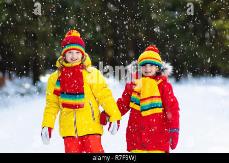 Les enfants jouent dans la neige. Les enfants jouer dehors sur le jour d'hiver enneigé. Garçon et fille attraper des flocons de neige dans la tempête. Frère et sœur throwing snow Banque D'Images