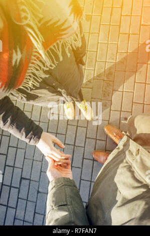 Vue à la première personne du couple holding hands. Couple d'amoureux se tenant la main lors de la marche au coucher du soleil. Concept d'excuses Banque D'Images