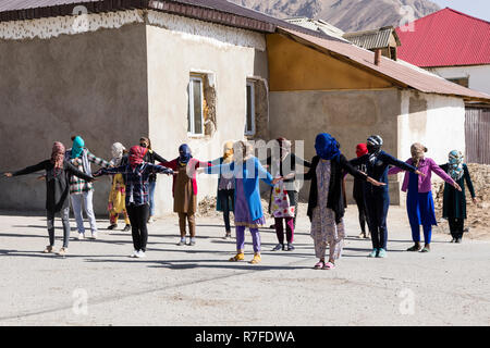 Murghab, le Tadjikistan, le 23 août 2018 : les filles et les jeunes femmes kirghizes pratiquent une danse sur l'aire d'une école à Mourgab. Contre les forts Banque D'Images