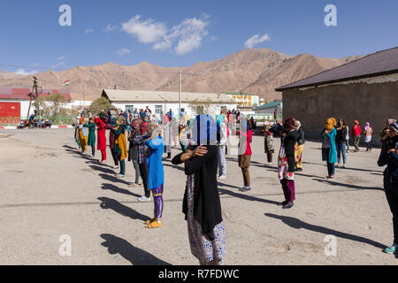 Murghab, le Tadjikistan, le 23 août 2018 : les filles et les jeunes femmes kirghizes pratiquent une danse sur l'aire d'une école à Mourgab. Contre les forts Banque D'Images