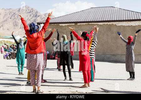 Murghab, le Tadjikistan, le 23 août 2018 : les filles et les jeunes femmes kirghizes pratiquent une danse sur l'aire d'une école à Mourgab. Contre les forts Banque D'Images