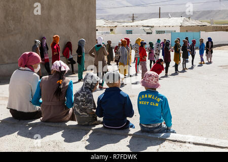 Murghab, le Tadjikistan, le 23 août 2018 : les filles et les jeunes femmes kirghizes pratiquent une danse sur l'aire d'une école à Mourgab. Contre les forts Banque D'Images