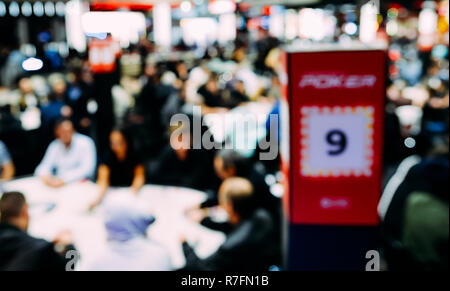 Flou artistique délibérément de voir grand tournoi de poker à tables multiples. Les joueurs assis à table et les concessionnaires s'occupant des cartes. Tournoi de grand champ Banque D'Images