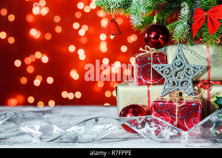 Étoile d'argent et des cadeaux sur une planche en bois recouverte de neige sous un arbre de Noël sur fond brillant avec copie espace pour le texte. Banque D'Images