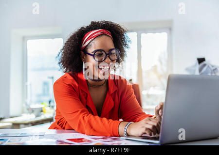 Le poil court African American Woman laughing ouvertement en position assise Banque D'Images