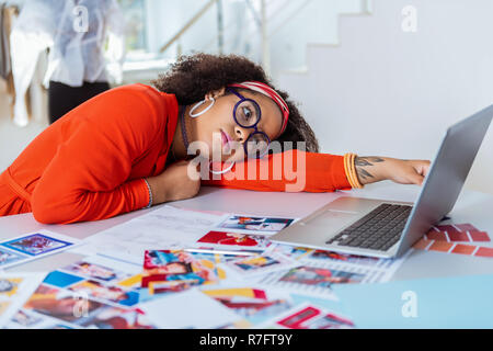 Appel triste femme exotique couchée sur le table de travail Banque D'Images