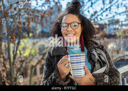 Smiling la peau sombre dame ayant de l'ombre à paupières bleu clair Banque D'Images