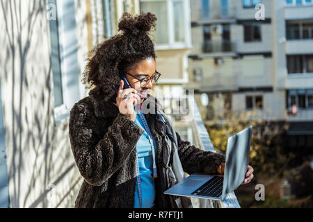 Smiling girl avec bun sur sa tête à parler sur son téléphone Banque D'Images