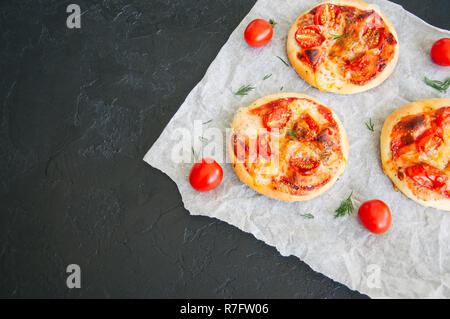 Mini pizzas margheritas sur un papier sulfurisé sur une pierre noire ba Banque D'Images