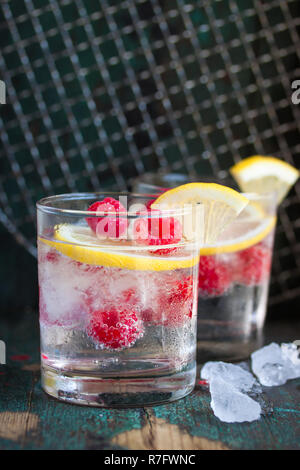 Rhume d'été maison citron framboise cocktail avec de l'eau pétillante et écrasées dans des verres glacés sur un arrière-plan vintage, gros plan Banque D'Images