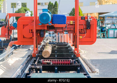 Entreprise de menuiserie. Machine de découpe de bois. Grumes pour bois de chauffage partiellement sur une fraiseuse à bois portable Banque D'Images