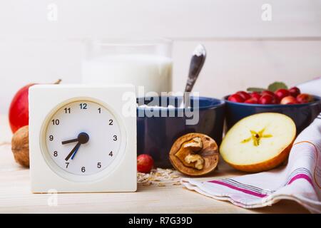 Petit-déjeuner sain - réveil, lait, le gruau, les canneberges, les noix, les pommes sur une table en bois Banque D'Images