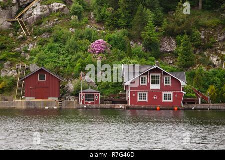 Maisons rouges sur un lac norvégien côte Banque D'Images