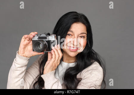 Photographe. Dame matures isolés sur gris pour prendre des photos avec camera film cheerful close-up Banque D'Images