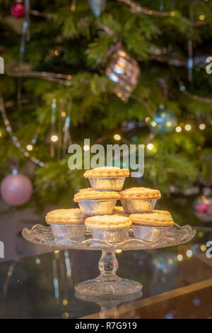 Plateau de petits pâtés en feuille d'argent des wrappers en face de l'arbre de Noël Banque D'Images