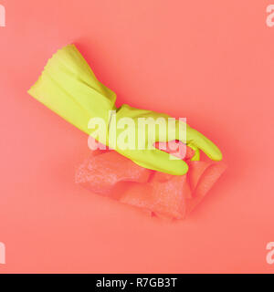 Gant de protection en caoutchouc vert avec chiffon corail sur fond corail. Image conceptuelle en tons de couleurs tendance de l'année 2019 de coraux vivants et de soufre SP Banque D'Images