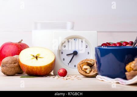 Petit-déjeuner sain - réveil, lait, le gruau, les canneberges, les noix, les pommes sur une table en bois Banque D'Images