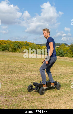 Jeune homme européen rides mountainboard électrique offroad Banque D'Images