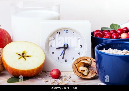 Petit-déjeuner sain - réveil, lait, le gruau, les canneberges, les noix, les pommes sur une table en bois Banque D'Images