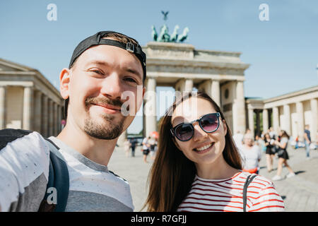 Belle jeune couple contre selfies l'arrière-plan de la porte de Brandebourg à Berlin en Allemagne. Banque D'Images