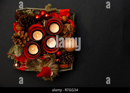 Vue de dessus de la guirlande avec quatre bougies, sapin, boules de Noël, un nain et un cône de sapin sur fond noir Banque D'Images