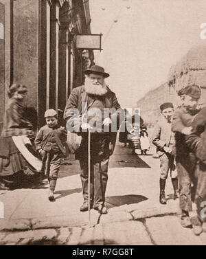 La vie de groupe de folk dans Victorian days... Un aveugle avec son bâton blanc et d'un entourage d'enfants en grande Homer Street, Liverpool, Merseyside, Angleterre Banque D'Images