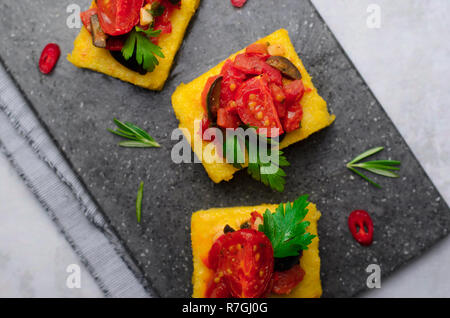 Les morsures de la polenta à la Tomate et olives noires Topping, Polenta apéritif, en-cas délicieux, Vue du dessus Banque D'Images