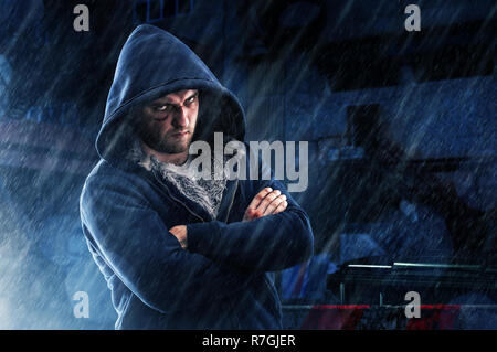 L'homme suspect avec ecchymose et frappa les poings in hoodie sur rue de nuit sous la pluie. Personne criminel, hooligan fighter Banque D'Images
