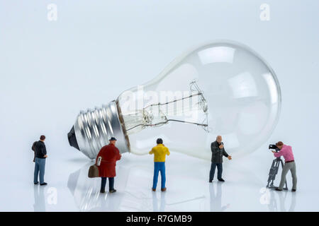 Figures miniatures près d'une ampoule, conceptual image Banque D'Images