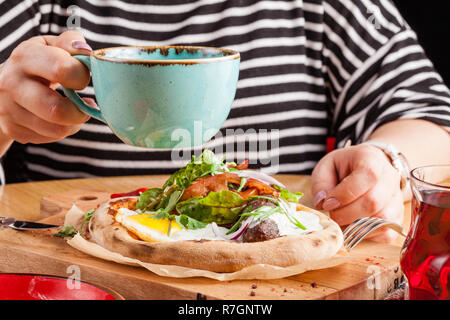 Petit-déjeuner anglais femelle manger des oeufs brouillés avec bacon, saucisses et légumes, gros plan Banque D'Images
