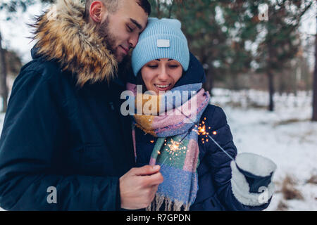 Beau couple aimant cierges brûlant dans la forêt d'hiver. Noël et Nouvel an fête concept Banque D'Images