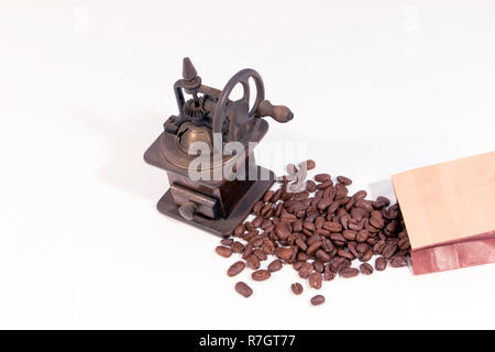 Ancien moulin à café en bois manuel avec roue dentée et dispersés, les grains de café sur fond blanc Banque D'Images