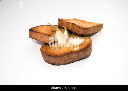 Tranches de pain grillé avec appétit croûte croustillante et quelques gousses d'ail germé isolé sur fond clair Banque D'Images