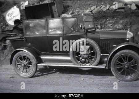 Années 20, deux dames assis à l'arrière d'un Morris 'Oxford Bullnose' open tourer 4 places de stationnement automobile sur une route de gravier. Un signe de haute qualité Pratts motor spirit, d'éthyle de Pratt peut être vu sur le côté de la route. Banque D'Images