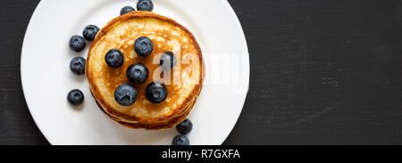 Crêpes aux bleuets sur une plaque ronde blanche sur fond sombre, vue du dessus. Copier l'espace. Mise à plat, les frais généraux, d'en haut. Banque D'Images