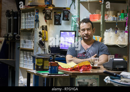 Pylos, Grèce - Octobre 2th, 2018 : Portrait d'un homme assis à son bureau, propriétaire d'un magasin de peinture dans la région de Pylos (Grèce). Banque D'Images